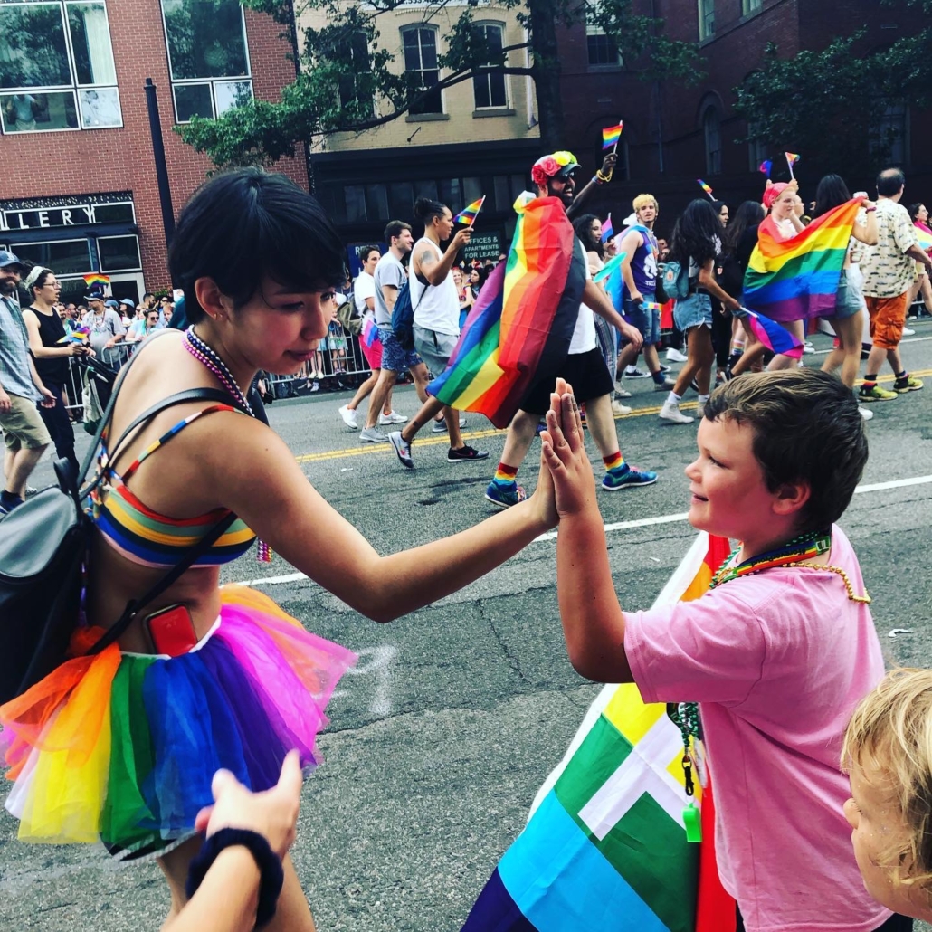 Woman in pride colors high fiving kids. We all deserve to be in a healthy and supportive environment. That is why we have LGBTQ therapists to help. Begin LGBTQ counseling in Florida for support today!