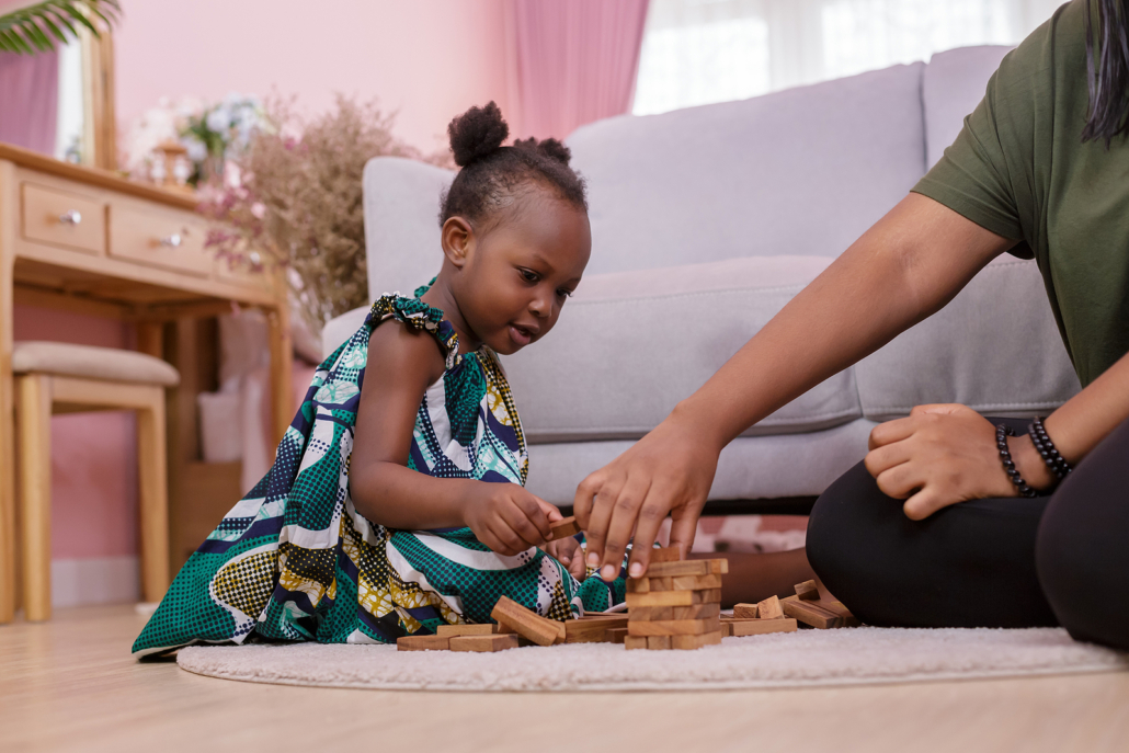 Young african girl in cute green dress playing with parent. Play is how children communicate, so why not let them communicate with a play therapist. They will be able to be heard in online play therapy in florida and connect better with you. Begin online therapy!