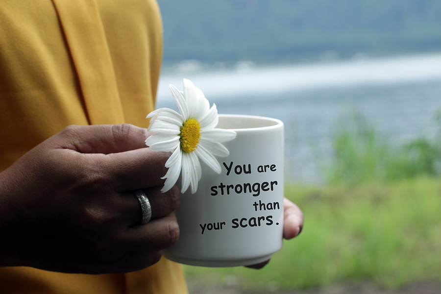 Picture of woman holding mug with flower saying " you're stronger than your scars". Trauma takes it toll. Move forward with guidance from a trauma therapist. Begin PTSD treatment and trauma therapy in Florida. We can assist with complex trauma, secondary trauma, and medical trauma.