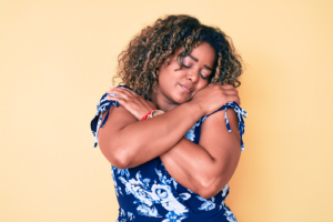 Woman hugging herself. If you need support, we are here to help, Some of our therapists are black therapist and BIPOC therapists. See if support BIPOC therapy in Florida is right for you., Call now for online therapy in Florida..