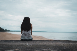 Woman sitting on beach looking thoughtfully. Coping skills for stress in Brevard County, FL is a necessity to dealing with anxiety. See how anxiety treatment in Brevard County, FL with a skilled anxiety therapist in florida can help!