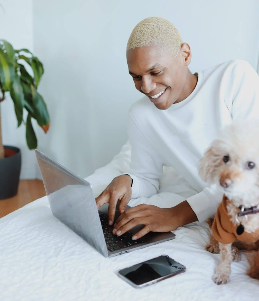 Black man smiling on computer with dog near by. If you're looking for support, online therapy in Florida can help you with anxiety, depression, trauma, and more. Our skilled online therapists in Florida are here to provide you with the support you need. Call now for online life coaching in Florida, Texas and beyond, too!
