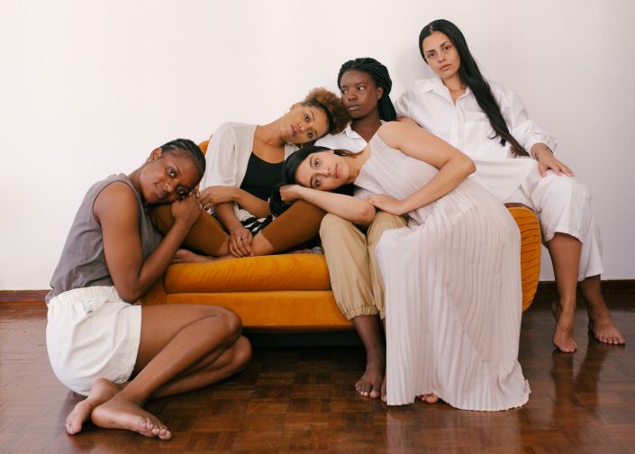 BIPOC women laying against each other and yellow chair. We are all different and that is with purpose. Begin BIPOC therapy in Florida if you are struggling with accepting yourself. Therapy for people of color can help you find peace.