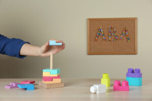 Child playing with colorful blocks on tower. It may be time to talk with a registered play therapist if communication and connection are offer with your child. Learn more about play therapy in Florida and inquire about play therapy for ADHD today!