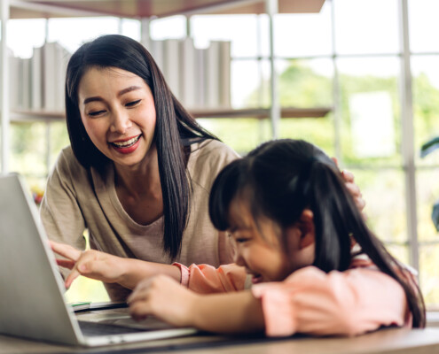 mom and daughter looking at laptop. It may be time to talk with a registered play therapist if communication and connection are offer with your child. Learn more about play therapy in Florida and inquire about play therapy for ADHD today!