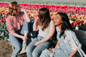 Group of teens smiling and laughing in tulip field. Early intervention with therapy for teens in florida can help your teen manage self-harm, anxiety, depression, and more. Begin online therapy in Florida today!