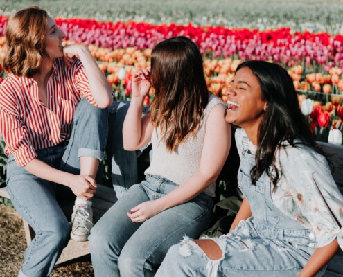 Group of teens smiling and laughing in tulip field. Early intervention with therapy for teens in florida can help your teen manage self-harm, anxiety, depression, and more. Begin online therapy in Florida today!