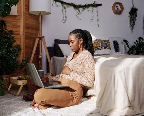 Woman pregnant on laptop. Are you feeling mom guilt or as if you are an overwhelmed mom? Then therapy for new moms in Florida can help. Learn more and begin online therapy when you're ready.