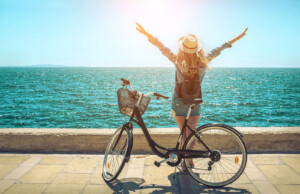 Woman on near bike with arms outstretched toward ocean. Work stress in florida is inevitable no matter how much you love your job. Learn how to deal with stress at work in a healthy and manageable way. Or try anxiety treatment and stress therapy in Brevard County today!