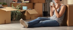 Woman sitting on ground near moving boxes drinking tea. If you are looking for help with anxiety, depression, stress, or trauma, then trying mindfulness for beginners in Florida can help. Call now to talk with an online therapist and see if online therapy in Florida can support you.