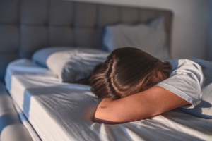 woman laying head on bed. Do you have a young adult at home that doesn't seem to want to move out or leave? We might be able to explain why, Read more and figure out what steps to take next!