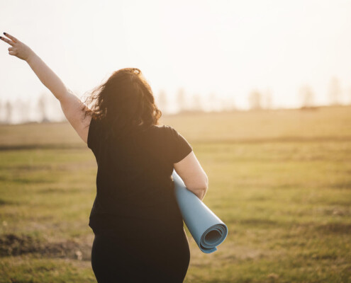 A woman holds up a peace sign while carrying a yoga mat. Learn how an online therapist in Brevard County, FL can help you feel restored and healed. Contact a trauma therapist in Florida to learn more about stress therapy in Florida today.