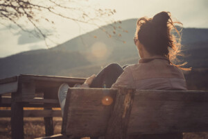 A woman sits on a bench while looking pensively out at a sunny landscape. Learn how an online therapist in Brevard County, FL can help you feel restored and healed. Contact a trauma therapist in Florida to learn more about stress therapy in Florida today.