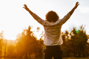 A person raises their hands as they watch the rising sun. This could represent the support a trauma therapist in Florida can offer from home via online therapy in Florida. Learn more about self-love coaching in Florida and other services today.