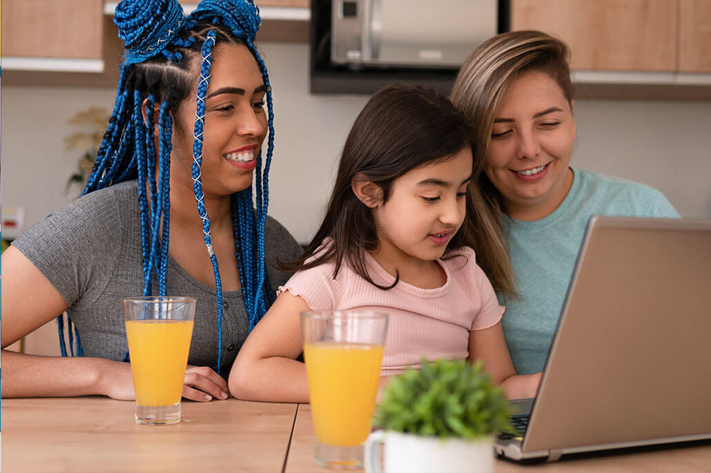 Two women with their child at a laptop