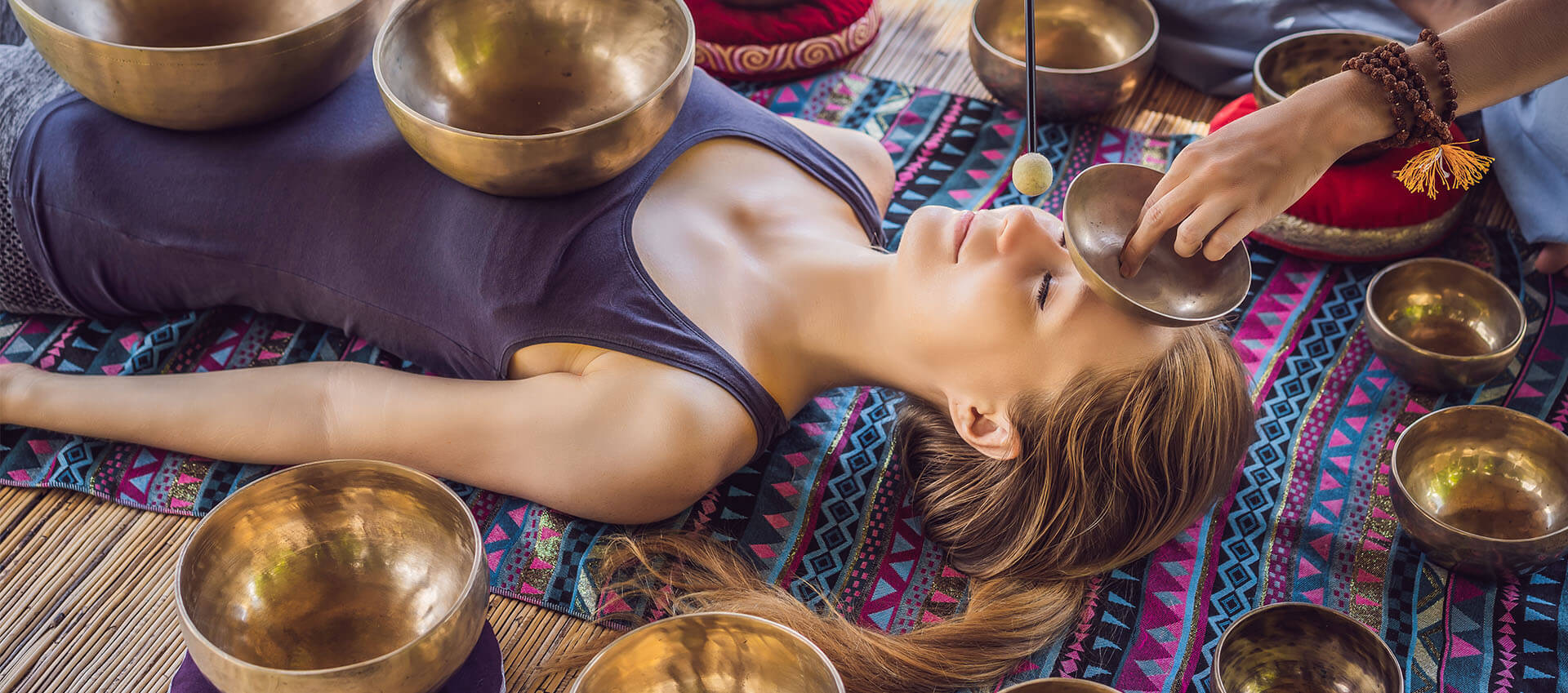 Woman lying on her back with sound bowls on and around her body
