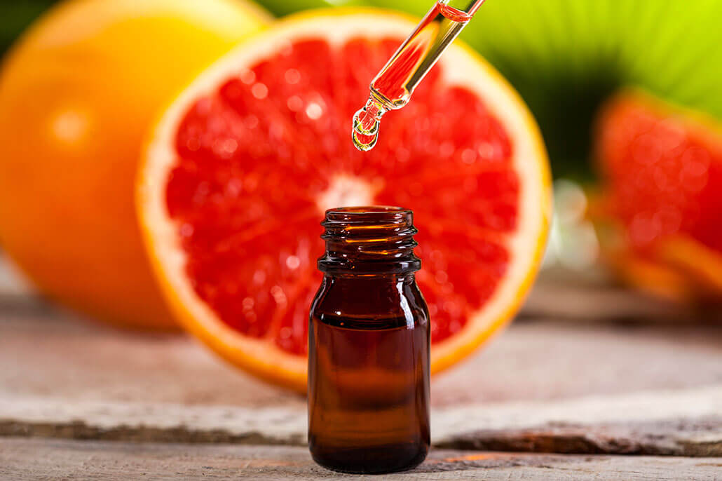 Essential oil bottle and dropper with a slice of grapefruit in the background