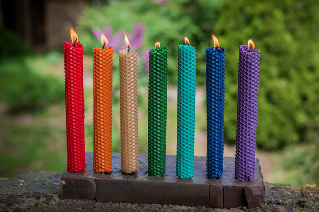 Seven colorful candles sitting on a pedestal outside.