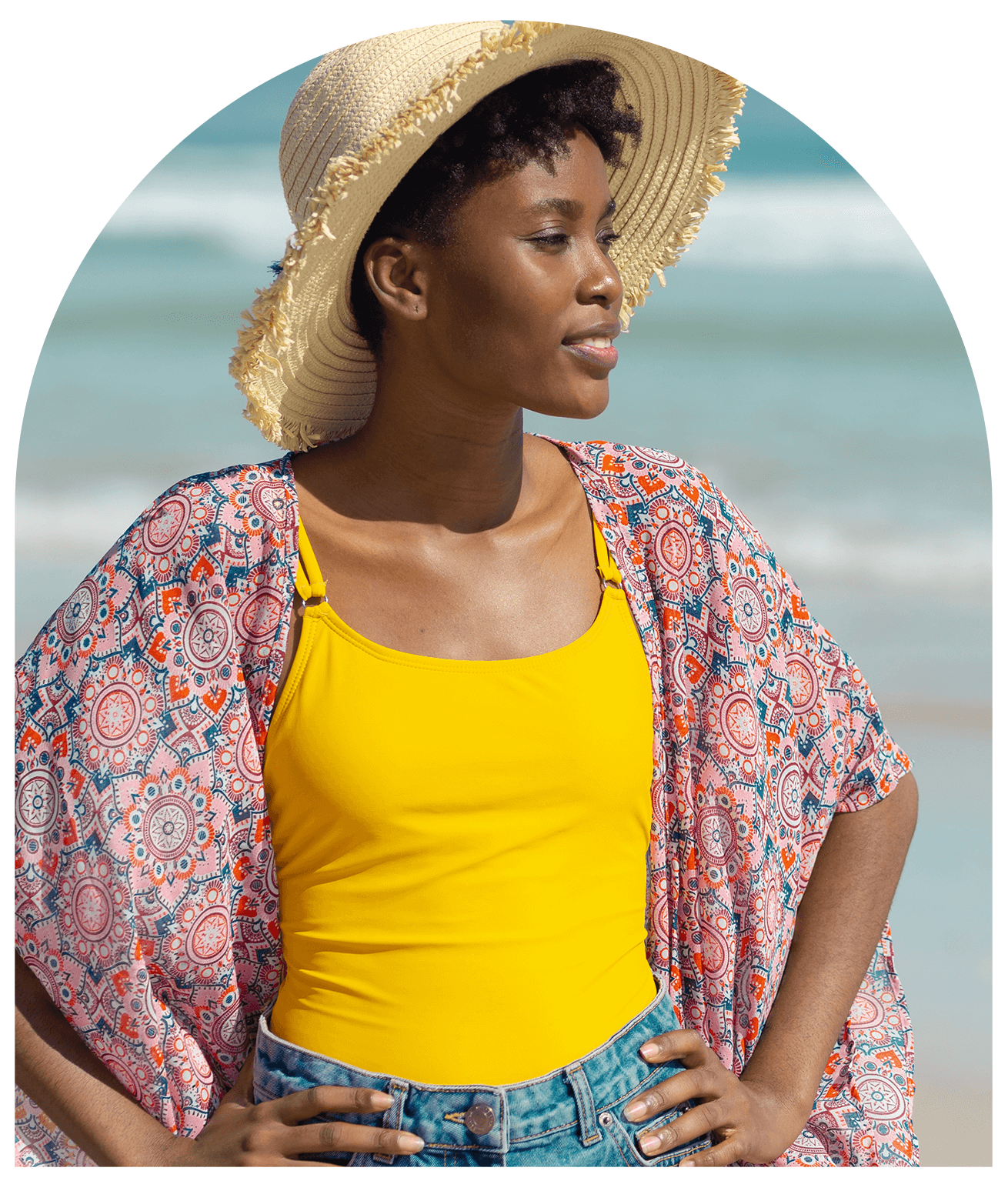 Black woman with hands on her hips gazes out along a beach