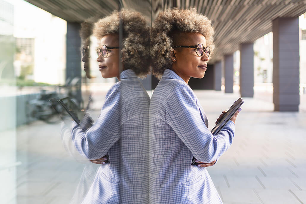 Black woman stands against her reflection in an office window