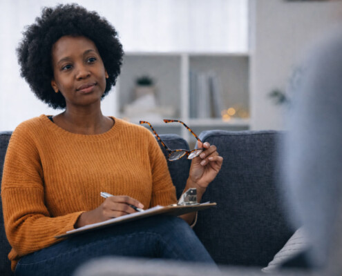 A calm attentive BIPOC therapists listens to a client