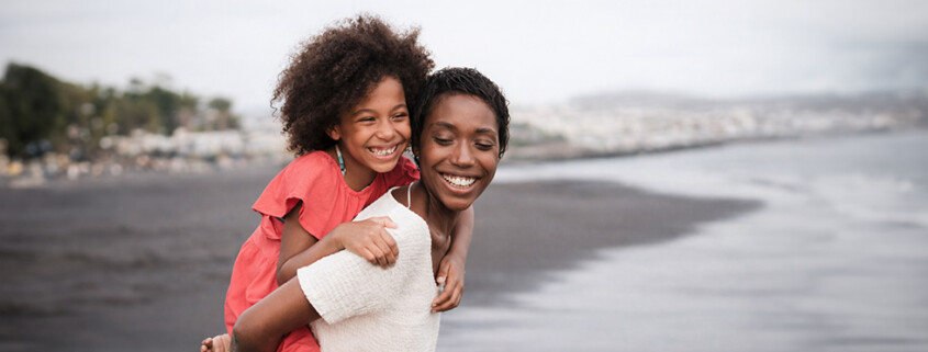 A BIPOC mom with her daughter on a Florida beach