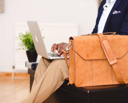 A man in a suit types on his laptop with a leather briefcase resting beside him. Can burnout build quietly behind a calm, put-together appearance at work? A stress and anxiety therapist in Florida can help you recognize the signs before they add up.