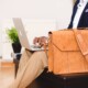 A man in a suit types on his laptop with a leather briefcase resting beside him. Can burnout build quietly behind a calm, put-together appearance at work? A stress and anxiety therapist in Florida can help you recognize the signs before they add up.