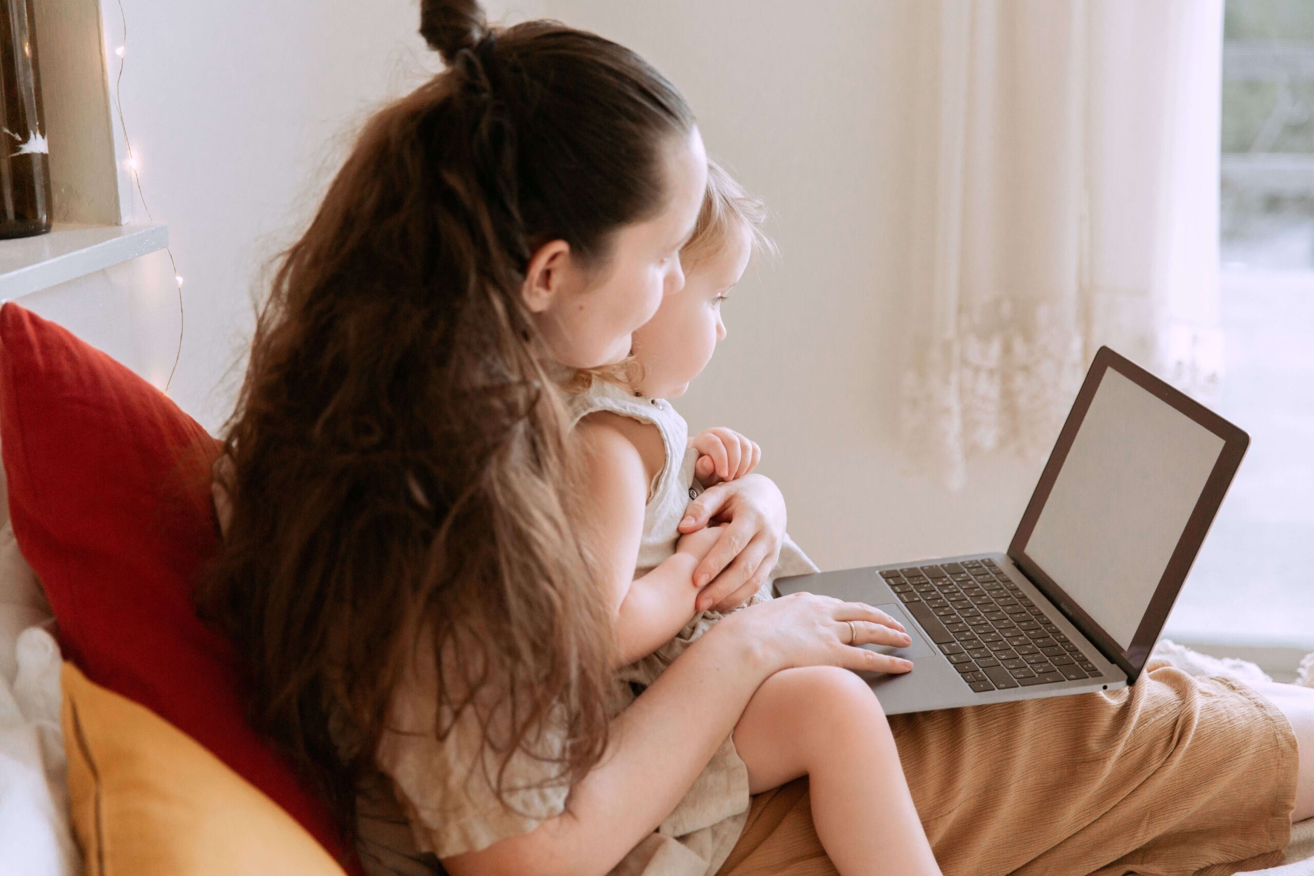 A mother holds her toddler on her lap while working on a laptop together. Can burnout affect how present you feel with the people who know you best? A stress and anxiety therapist in Florida can help you find balance between work and family life.
