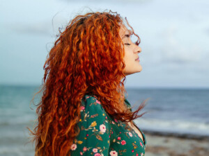 Woman taking a deep relaxing breath at the ocean shore